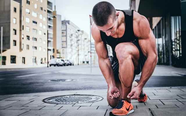 a Good Fitness athlete tying his shoe laces